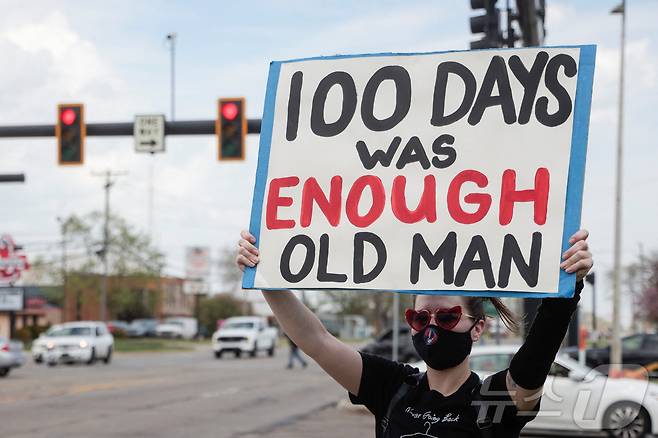 지난 29일(현지시간) 미국 미시간주 워런의 머콤카운티에서 열리는 도널드 트럼프 대통령 취임 100일 기념 행사장 앞에서 한 시민이 '100일이면 충분하다'라는 플래카드를 들고 시위를 벌이고 있다. ⓒ 로이터=뉴스1 ⓒ News1 류정민 특파원