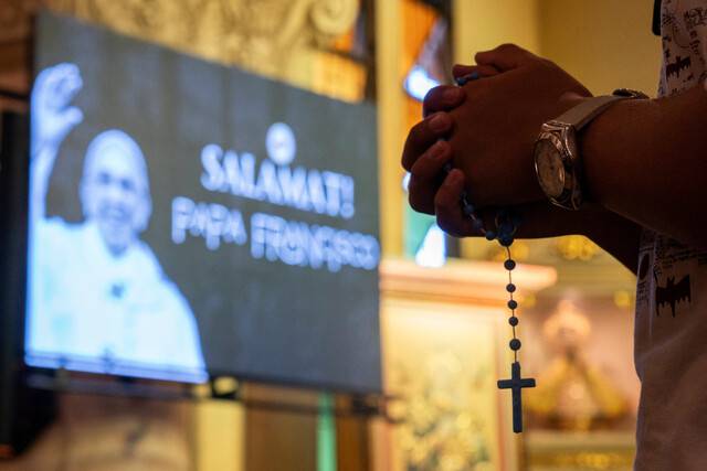 2025년 4월26일 필리핀 수도 마닐라의 한 성당에서 묵주를 손에 든 신자가 교황 프란치스코의 장례식 생방송을 지켜보고 있다. REUTERS 연합뉴스