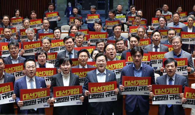 박찬대(앞줄 가운데) 더불어민주당 원내대표를 비롯한 의원들이 4일 국회에서 열린 긴급 의원총회에서 대법원 규탄 팻말을 들고 구호를 외치고 있다. 연합뉴스