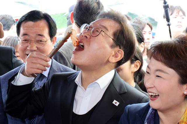민심을 청취하는 '경청 투어'에 나선 이재명 더불어민주당 대선후보가 10일 경남 함안군 가야시장 반찬가게에서 김치를 맛보고 있다. 뉴시스