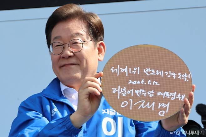 (화성=뉴스1) 안은나 기자 = 이재명 더불어민주당 대통령 후보가 제21대 대통령 선거 공식 선거운동 첫날인 12일 오후 경기 화성시 동탄 센트럴파크 음악분수중앙광장에서 '세계1위! 반도체 강국 도약!'이라고 쓴 반도체 웨이퍼를 들어 보이고 있다. (공동취재) 2025.5.12/뉴스1 Copyright (C) 뉴스1. All rights reserved. 무단 전재 및 재배포, AI학습 이용 금지. /사진=(화성=뉴스1) 안은나 기자