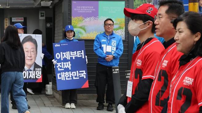 제21대 대통령 공식 선거운동 둘째 날인 13일 서울 서대문구 한 거리에서 기호 1번 더불어민주당 이재명, 2번 국민의힘 김문수 후보 선거운동원들이 시민들에게 인사하고 있다. 연합뉴스