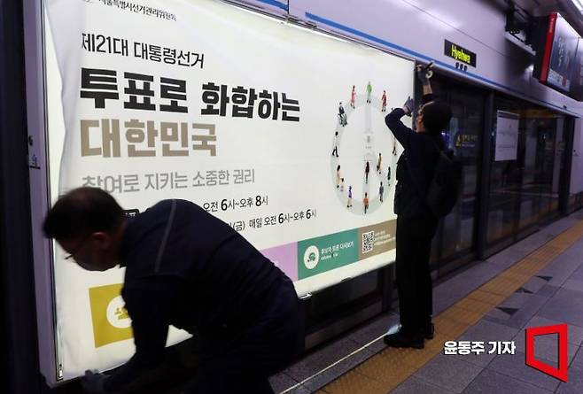 서울시선관위 관계자들이 서울 종로구 지하철 4호선 혜화역 승강장 스크린도어에 투표독려 홍보물을 첩부하고 있는 모습.