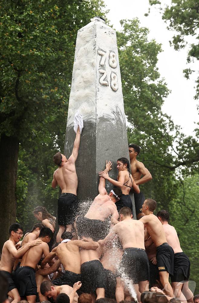 미국 해군사관학교에서 사관생도들이 14일(현지시간) 미국 메릴랜드 주 아나폴리스 미 해군 사관학교에서 '딕시 컵'을 떨어뜨리기 위해 인간 피라미드를 만들어 헌던 기념물 꼭대기에 오르고 있다. ⓒ 로이터=뉴스1