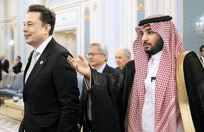 트럼프 사우디 순방에 머스크·젠슨 황 동행 - 일론 머스크(맨 왼쪽) 테슬라 최고경영자(CEO)와 젠슨 황(가운데) 엔비디아 CEO가 13일 리야드 궁정에서 무함마드 빈 살만 사우디아라비아 왕세자를 만나기 위해 안내를 받고 있다. 이날 시작된 도널드 트럼프 미국 대통령의 중동 순방에 미국 대표 빅테크 관계자들이 대거 동행했다. 이들은 걸프만 국가의 인공지능(AI) 인프라 구축에 투자할 계획을 내놨다. /AFP 연합뉴스