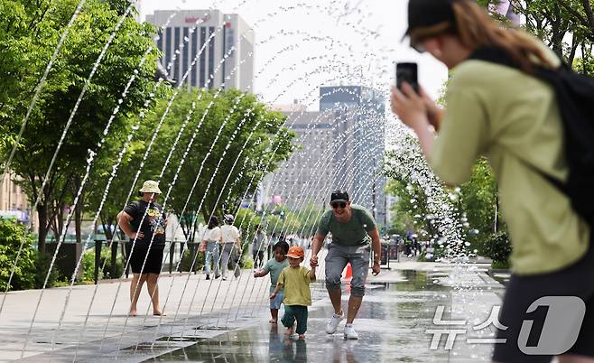 서울 낮 최고 기온 26도 등 초여름 날씨을 보인 14일 서울 광화문광장 분수터널에서 외국인 관광객들이 더위를 식히고 있다. 2025.5.14/뉴스1 ⓒ News1 허경 기자