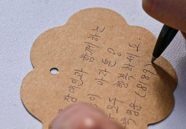 제491회 한국일보 거북이마라톤 '굿피플 발달장애인 인식개선을 위한 거북이마라톤'이 열리는 17일 오전 서울 중구 남산 백범광장에서 참가자들이 소망트리에 매달 희망 메시지를 적고 있다. 최주연 기자