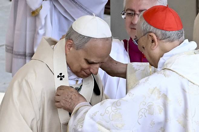 교황 레오 14세가 18일 바티칸 성 베드로 광장에서 열린 즉위 미사에서 이탈리아의 마리오 제나리 추기경으로부터 팔리움을 받고 있다. /AFP 연합뉴스
