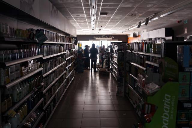 TOPSHOT - Employees stand inside a supermarket without lights in Burgos on April 28, 2025, during a massive power cut affecting the entire Iberian peninsula and the south of France. A \"massive\" power cut late on April 28, 2025 morning affected the whole of the Iberian peninsula and part of France, according to Portuguese electricity network operator REN. (Photo by CESAR MANSO / AFP)