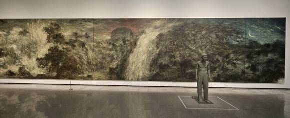 강요배 화백의 작품 2021년작인 가로 길이 15m가 넘는 대작 ‘수풍교향’과 그 작품 앞에 서 있는 화백 자소상의 모습. 제주 강동삼 기자