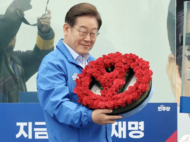 이재명 더불어민주당 대선 후보가 제21대 대통령선거 재외국민투표가 시작된 20일 경기 고양시 일산동구 일산문화공원에서 한 지지자에게 기표마크 모양의 장미를 받고 있다. 고양=오승현 기자