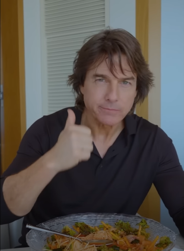 Tom Cruise flashes a thumbs-up as he samples spicy raw fish soup (Screengrab from YouTube)