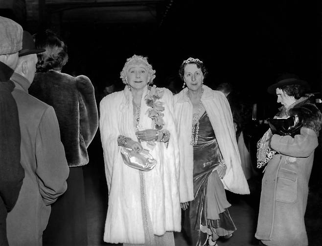 1943년 미국 사교계 인사 마리 밀러 카바노와 레이디 데시가 화려한 차림으로 채 뉴욕 메트로폴리탄 오페라에 도착하고 있다. 맨오른쪽 허름한 옷을 입은 여인이 그 앞을 지나친 모습은 빈부의 격차를 대비시키는 모습으로 비춰지는데 위지는 이 여인을 일부러 섭외해서 기다리다 촬영했다고 했다. 위지의 대표적인 연출 사진으로 꼽힌다.