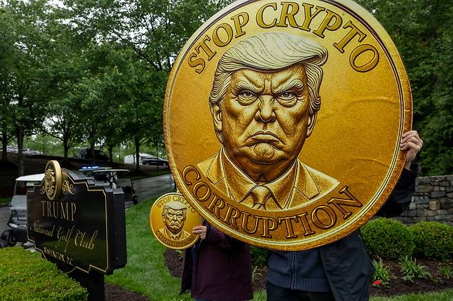 22일 미국 버지니아주 스털링 트럼프 내셔널 골프클럽 인근에서 트럼프 대통령의 암호화폐 관련 정책에 반대하는 활동가들이 시위를 벌이고 있다. /연합뉴스