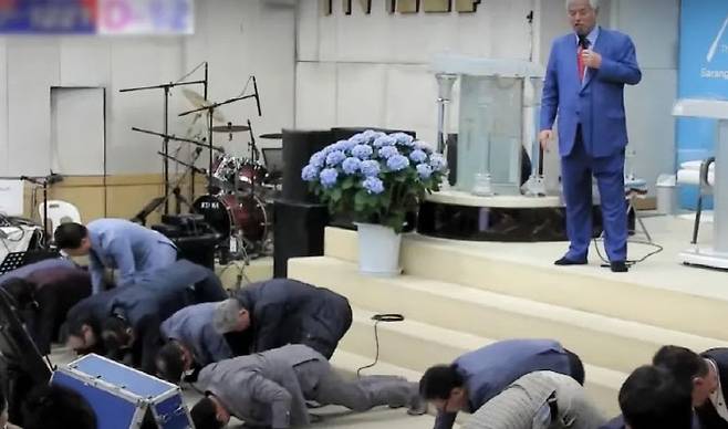 전광훈(오른쪽 위) 목사가 22일 사랑제일교회에서 “(집회 참가자 할당 인원을 데려오지 못한 사람은) 대가리를 박는다, 실시”라고 지시하자 지역 광역위원장들이 머리를 바닥에 대고 엎드려뻗쳐 자세를 취하고 있다. 유튜브 전광훈TV 영상 캡처