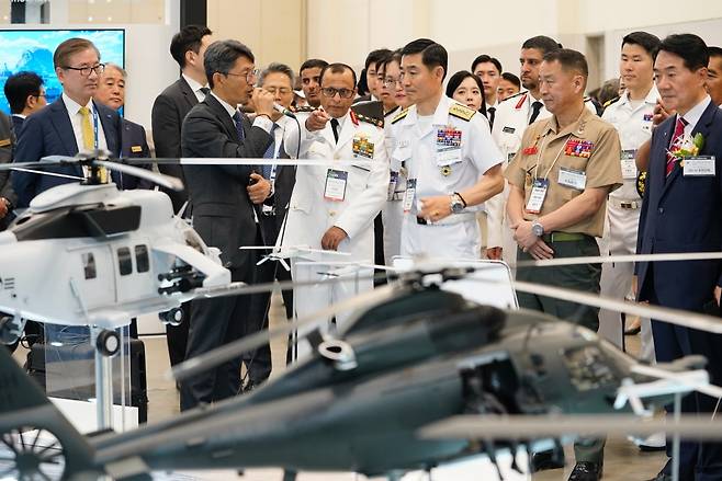 28일 부산 벡스코에서 개막한 제14회 국제해양방위산업전(MADEX) 'MADEX 2025'에서 한국항공우주산업(KAI) 관계자가 자사 부스를 방문한 해외 해군 관계자에게 상륙공격헬기(MAH)를 소개하고 있다(KAI 제공). 2025.05.28.