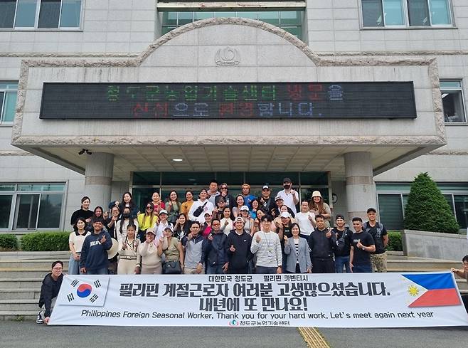 지난 23일 청도 지역농가에서 약 8개월간 근로한 외국인 계절근로자들이 송별행사를 마치고 기념사진을 찍고 있다. ⓒ청도군