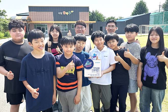 우리금융그룹이 지난 29일 지현초등학교에서 드림라운드 현판식을 개최했다. 드림라운드에 참가한 지현초등학교 학생 9명과 이영신 교장(뒷줄 왼쪽에서 3번째), 우리금융지주 박준태 부장(뒷줄 왼쪽에서 4번째)이 기념 사진 촬영을 하고 있다.