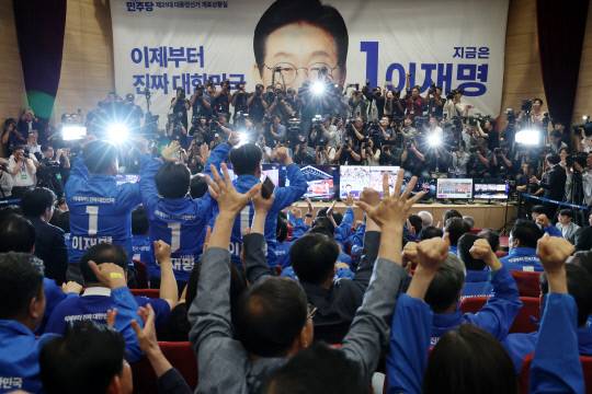 더불어민주당 박찬대, 윤여준 상임총괄선대위원장을 비롯한 선대위 관계자들이 3일 국회의원회관 개표상황실에서 제21대 대통령선거 지상파 출구조사 결과에서 이재명 후보가 51.7%로 앞서는 것으로 발표되자 환호하고 있다. 연합뉴스