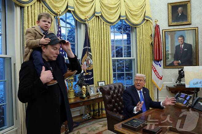 도널드 트럼프 미국 대통령이 2025년 2월 11일 미국 워싱턴 D.C.의 백악관 집무실에서 일론 머스크가 X Æ A-12를 어깨에 메고 연설하고 있다 ⓒ 로이터=뉴스1 ⓒ News1 박은정 기자