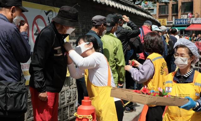 ▲어버이날인 8일 서울 종로구 탑골공원 앞에서 원각사 무료급식소 자원봉사자들이 어르신들의 가슴에 카네이션을 달아 드리고 있다. ⓒ연합뉴스