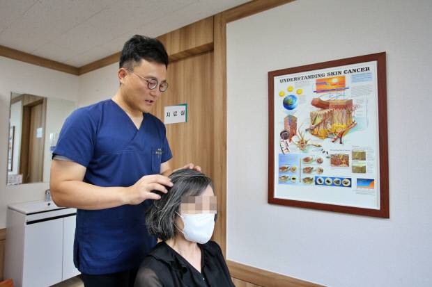 조선대병원 피부과 김민성 교수가 원형탈모 증상으로 내원한 환자를 진료하고 있다.