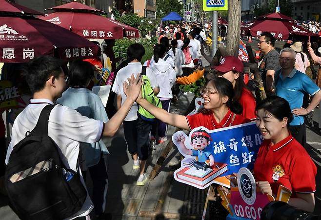 중국 전국 대학 입학시험인 가오카오(高考)가 7~8일 양일간 치러졌다. 베이징의 한 고등학교 앞에서 선생님들이 행운·합격을 의미하는 해바라기 무늬가 있는 빨간 셔츠를 입고 응시생들을 응원하고 있다. 선생님들은 깃발을 펴자마자 승리를 거두고, 물고기가 용문을 뛰어넘는다는 의미의 ‘치카이더셩·위에이롱먼’(旗开得胜·鱼跃龙门)이 쓰인 응원 팻말을 들고 있다. AFP연합뉴스