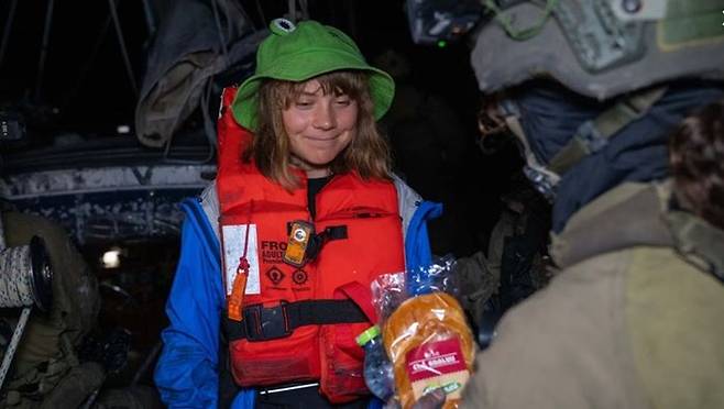 이스라엘 해군이 팔레스타인 가자지구로 향하던 매들린호를 차단한 9일(현지시간) 이 배에 타고 있던 스웨덴 환경운동가 그레타 툰베리가 이스라엘 군인으로부터 빵과 물을 건네받고 있다. ⓒ 이스라엘 외무부/연합뉴스