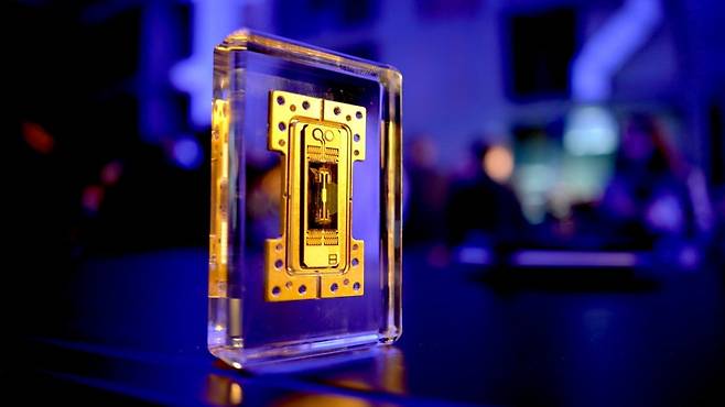 아이온큐의 이온 트랩 기반 양자컴퓨터 칩. 투명한 아크릴 블록 안에 전시된 형태로, 중앙의 금색 구조물은 이온을 포획하고 제어하는 데 사용되는 마이크로 전극 구조다. /사진=아이온큐
