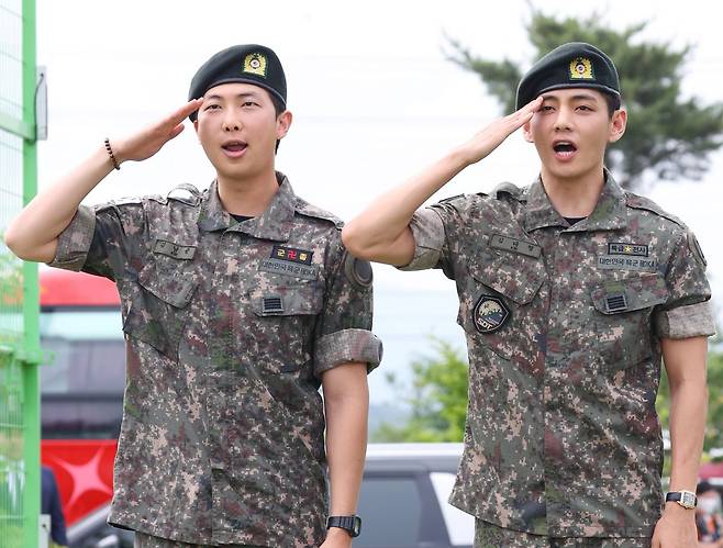 육군 현역 복무를 마치고 만기 전역한 그룹 방탄소년단(BTS) RM과 뷔가 10일 강원 춘천시 신북읍체육공원에서 취재진을 향해 거수경례하고 있다. 연합뉴스
