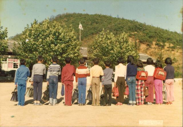 밀양운정초등학교 학생들이 국기하강식 때 가슴에 손을 올리고 서 있다(1980년).