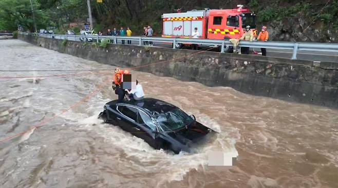 14일 오전 10시13분쯤 경북 청송군 청송읍 부곡리 하천으로 추락한 차량에 고립돼 있는 모녀를 119구조대가 구조하고 있다. 경북소방본부 제공