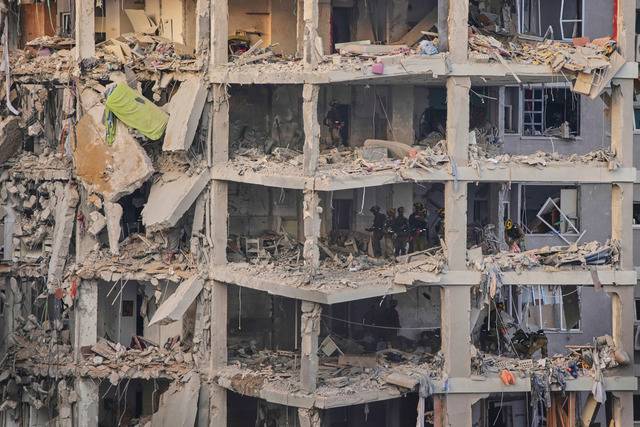 이스라엘 군인들이 15일(현지시간) 이란의 미사일 공격을 받아 뼈대만 남아 있는 텔아비브 인근 건물 내부를 수색하고 있다. AP연합뉴스