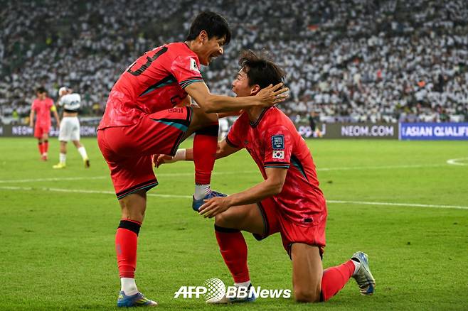 대한민국 축구대표팀 공격수 오현규(오른쪽)가 지난 6일 이라크 원정에서 골을 넣은 뒤 어시스트해준 전진우의 축구화를 닦아주는 세리머니를 하고 있다. /AFPBBNews=뉴스1