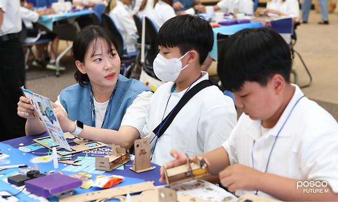 포스코퓨처엠 직원이 푸른꿈 환경캠프에 멘토로 나서 어린이와 함께 전기차 모형을 제작하고 있다. 포스코퓨처엠 제공