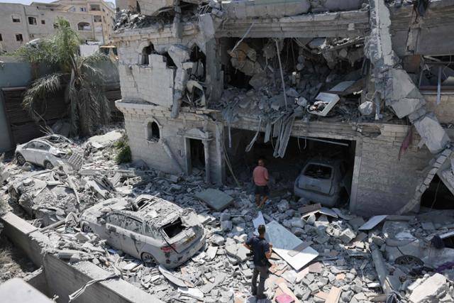 이스라엘 북부 마을 탐라의 주민들이 15일 전날 이란의 미사일 폭격으로 피해를 입은 건물을 살펴보고 있다. 탐라=AFP 연합뉴스