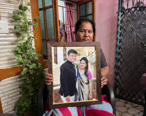 푸자-하싯 부부의 결혼사진을 들고 있는 푸자의 어머니.(사진 출처 : 더가디언)