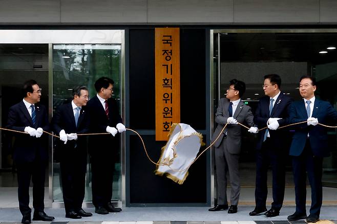이한주(왼쪽 세 번째) 국정기획위원장과 국정기획위원회 진성준, 김용범, 방기선 부위원장 등 참석자들이 16일 서울 종로구 정부서울청사 창성동 별관에서 열린 국정기획위원회 현판식에서 현판 제막을 하고 있다./뉴스1