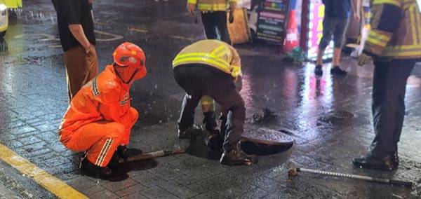 지난 14일 부산 연제구 한 도로에서 뚜껑이 열린 맨홀을 소방대원이 안전 조치하는 모습. 부산소방재난본부 제공