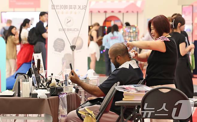19일 오후 서울 중구 DDP에서 열린 2025 코리아뷰티페스티벌를 찾은 외국인 관광객이 두피 메이크업 제품 체험을 하고 있다. 2025.6.19/뉴스1 ⓒ News1 장수영 기자