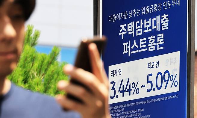 지난 15일 한 시민이 서울 시내 은행 앞 대출 홍보물을 지나고 있다. 연합뉴스