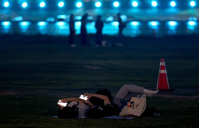 잔디밭에 누운 시민이 여유롭게 불꽃 쇼를 기다리고 있다.