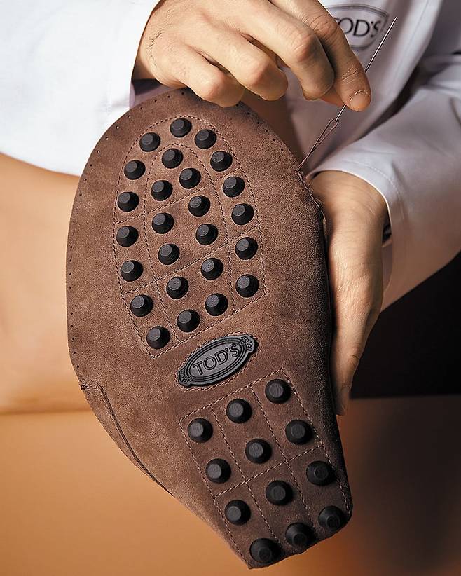 최대 35개의 레더 조각들로 이루어진 고미노 슈즈의 레더를 직접 손바느질로 이어 꿰매는 장인의 모습. /토즈 그룹 제공