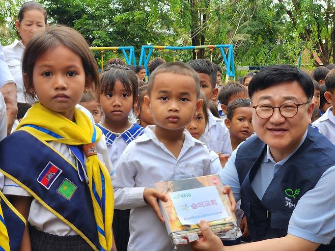 이선목(오른쪽) 숭의교회 목사가 캄보디아 알롱벵의 틀라초등학교 학생들에게 학용품을 전하고 있다.