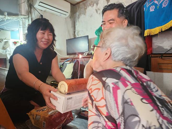 이현걸(가운데) 목사와 자원봉사자 김현순(왼쪽)씨가 김옥란(가명) 할머니에게 생일 케이크를 전달하고 있다.