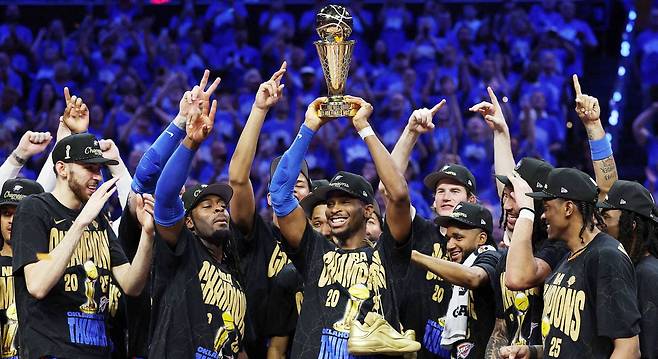 23일 NBA 챔피언에 오른 오클라호마시티 선더의 샤이 길저스 알렉산더가 파이널 MVP 트로피를 높이 들어 올리자 동료들이 함께 기뻐하고 있다. 길저스 알렉산더는 정규리그 득점왕과 MVP, 파이널 MVP를 석권한 역대 네 번째 선수가 됐다. /AFP 연합뉴스