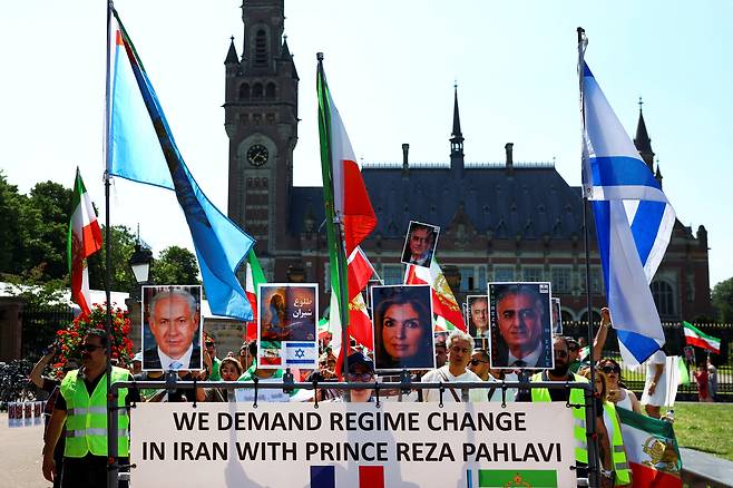 시위대가 21일 네덜란드 헤이그에서 열리는 NATO 정상회담을 앞두고 이란 정권에 항의하는 시위를 벌이는 동안 이스라엘 총리 베냐민 네타냐후, 망명 중인 이란 레자 팔라비 왕자, 야스민 팔라비 사진을 흔들고 있다. /연합뉴스