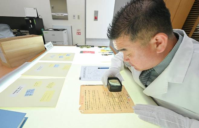 23일 충남 계룡대 육군기록정보관리단에서 열린 중요 역사기록물 복원사업 현장 공개에서 복원 관계관이 확대경을 이용해 보전 기록물의 손상도를 확인하고 있다. 사진=육군 제공