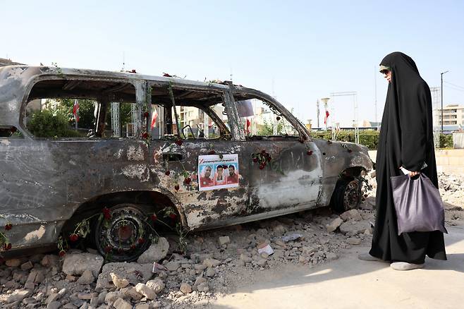 진정한 평화는 언제 23일(현지시간) 이란 테헤란에서 이스라엘 공습으로 불탄 적신월사 구급차를 한 여성이 바라보고 있다. EPA연합뉴스