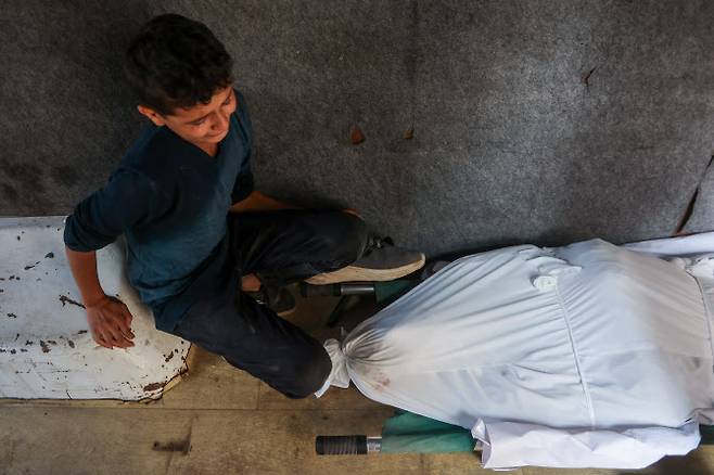 24일(현지시간) 가자지구 알 시파 병원에서 한 소년이 구호품을 구하려다 사망한 남성의 시신 앞에서 슬퍼하고 있다. (사진=AFP)